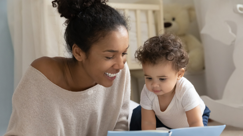 A woman is reading a book to a baby.