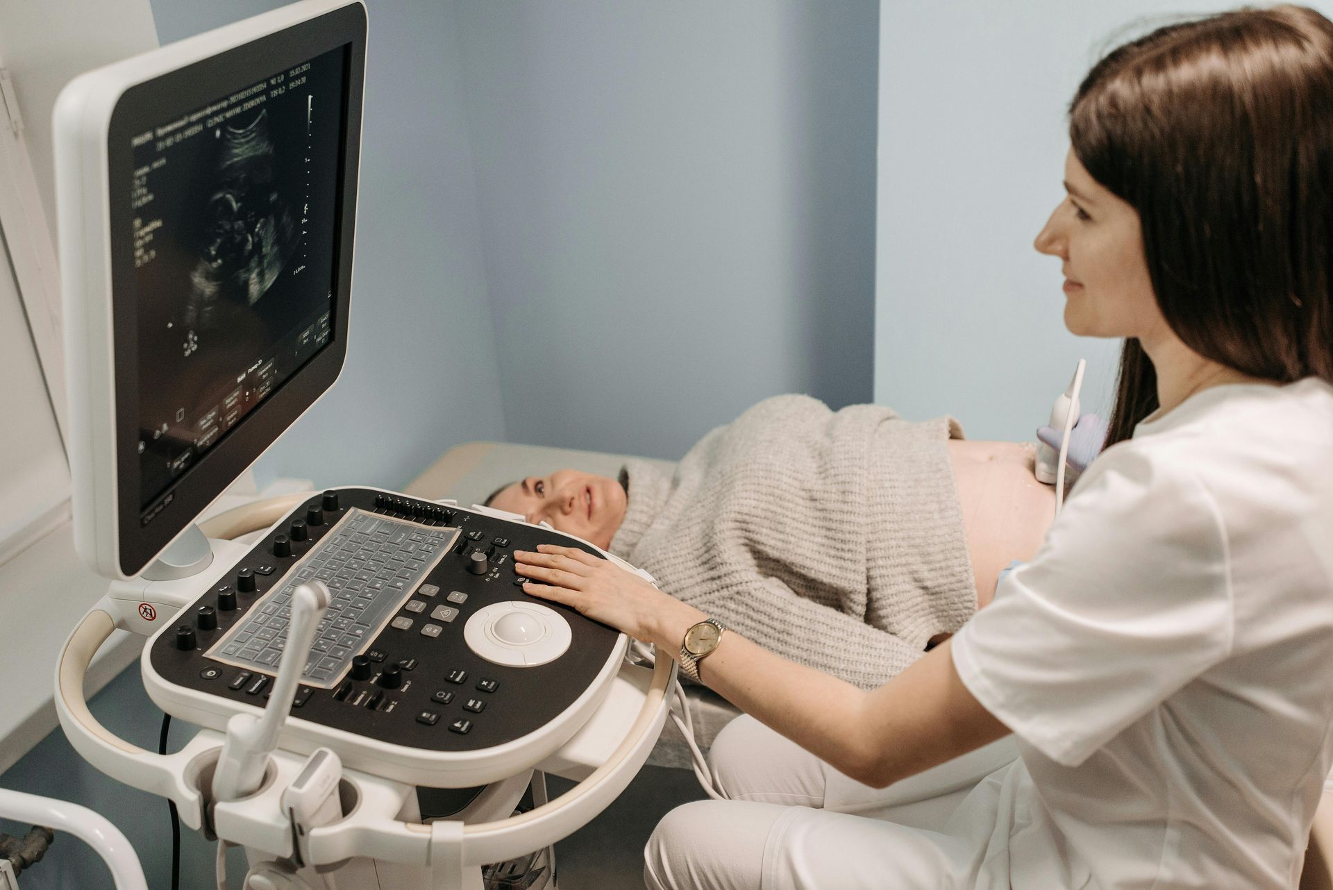 A nurse is using an ultrasound machine on a pregnant woman.