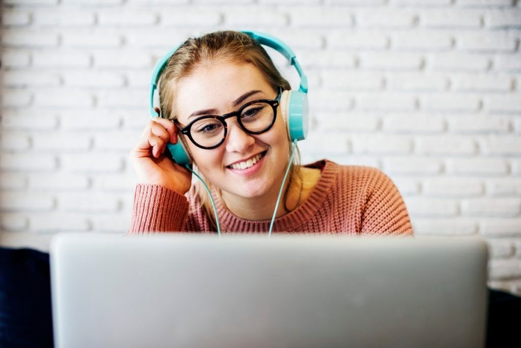 A woman wearing headphones is sitting in front of a laptop computer.