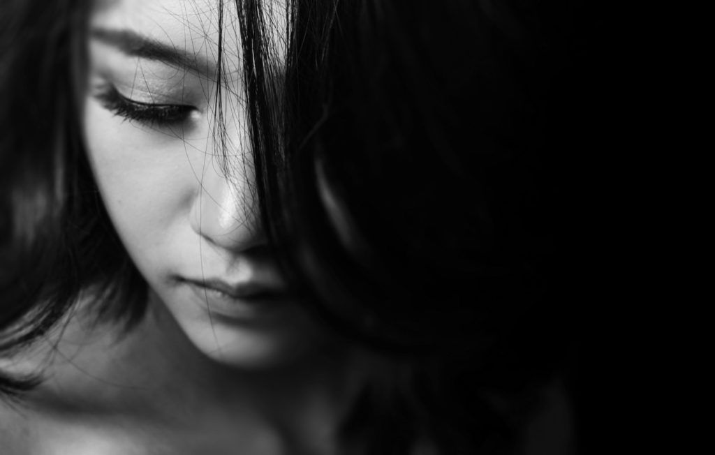 A black and white photo of a woman 's face with her eyes closed.