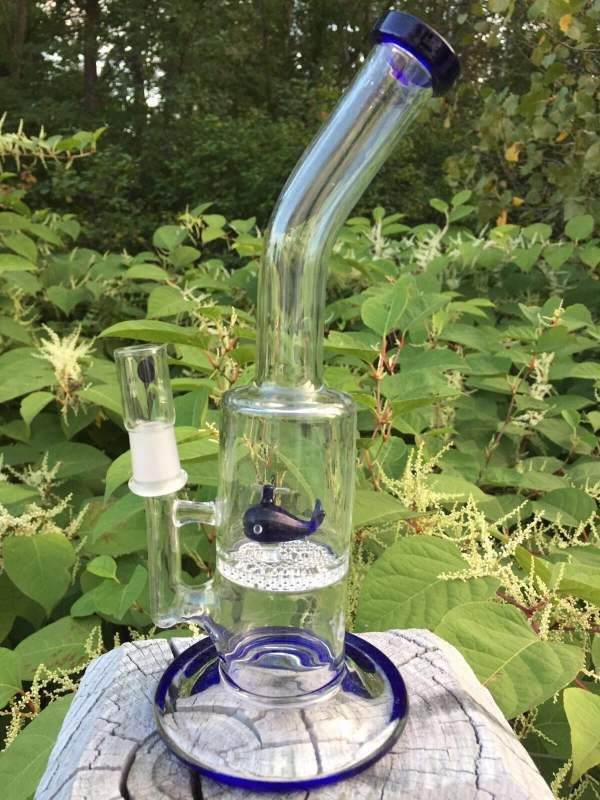 A glass bong with a fish on it is sitting on top of a rock