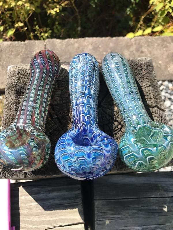 Three glass pipes are sitting on top of a wooden table