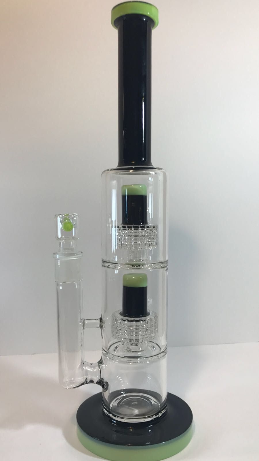 A black and green glass bong is sitting on top of a white table