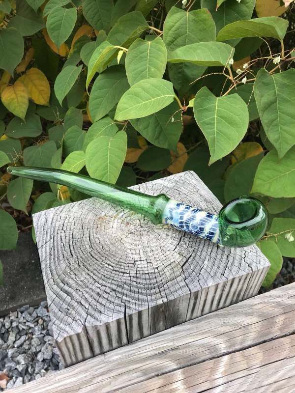 A green glass pipe is sitting on top of a wooden block