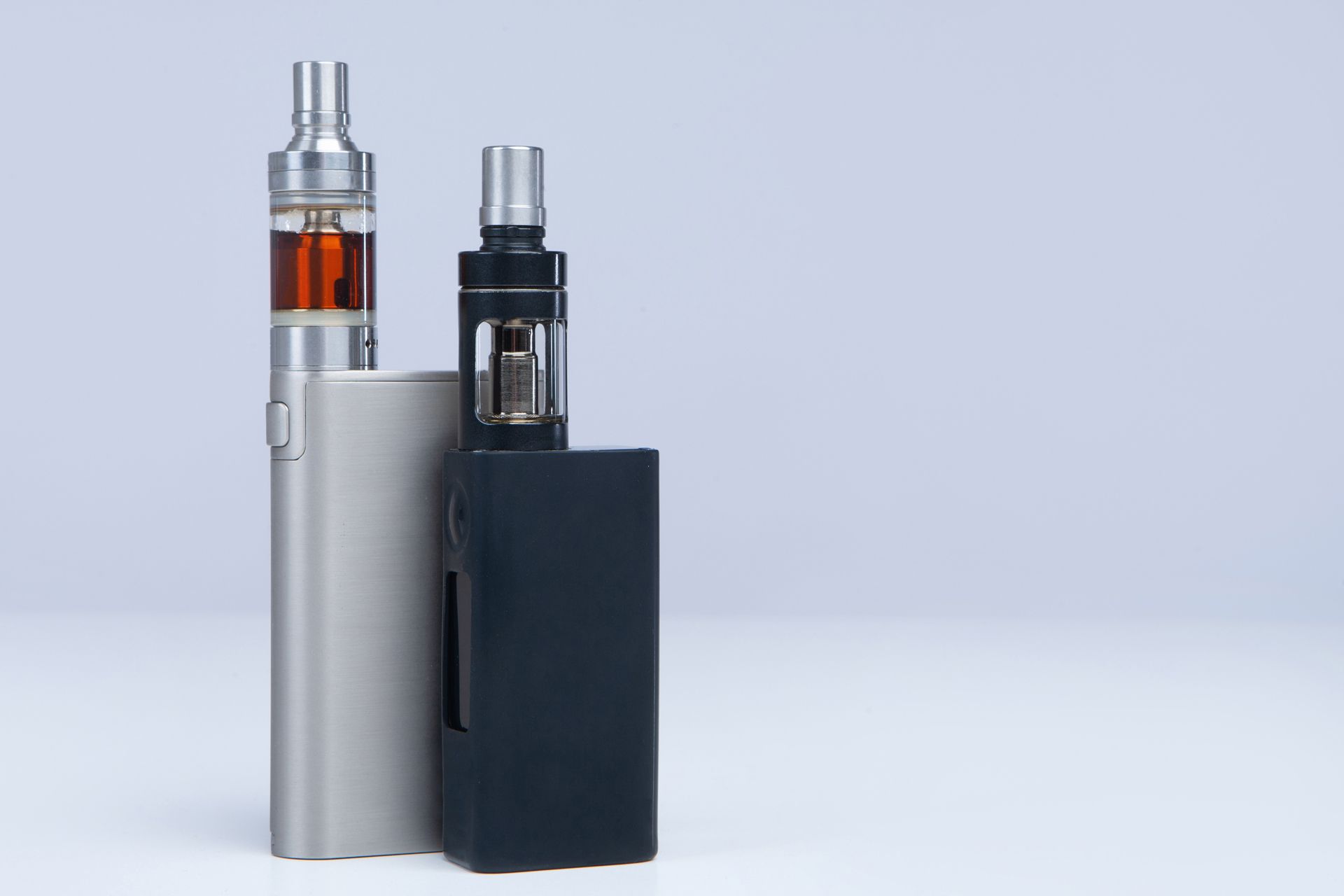 Three electronic cigarettes are sitting next to each other on a white surface