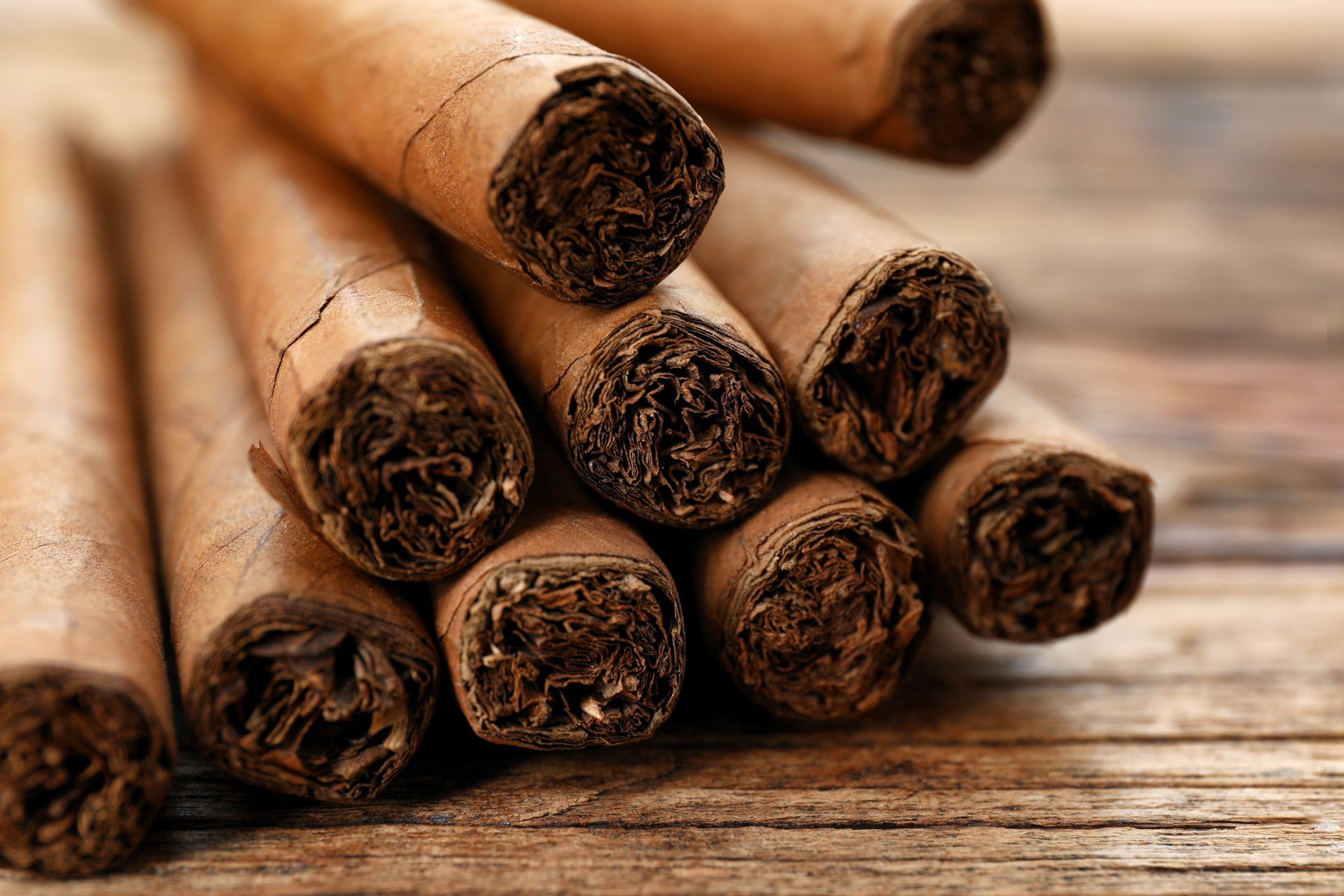 A bunch of cigars are stacked on top of each other on a wooden table