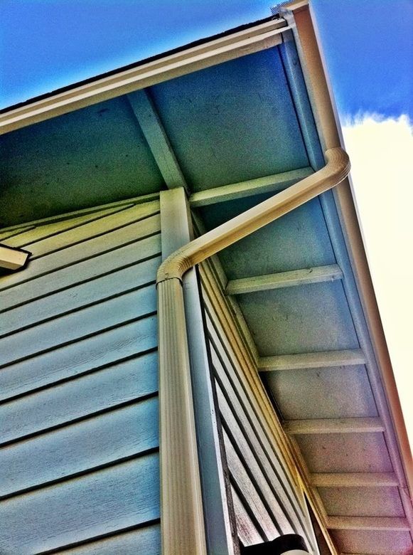 A gutter on the side of a house with a blue sky in the background