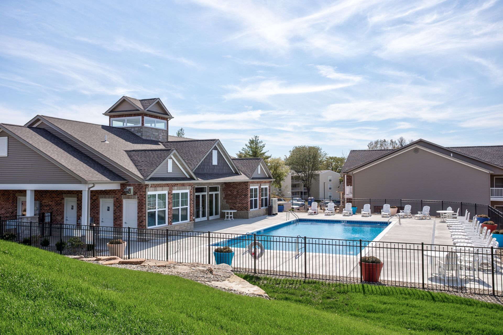A large swimming pool is surrounded by a fence in front of a house.