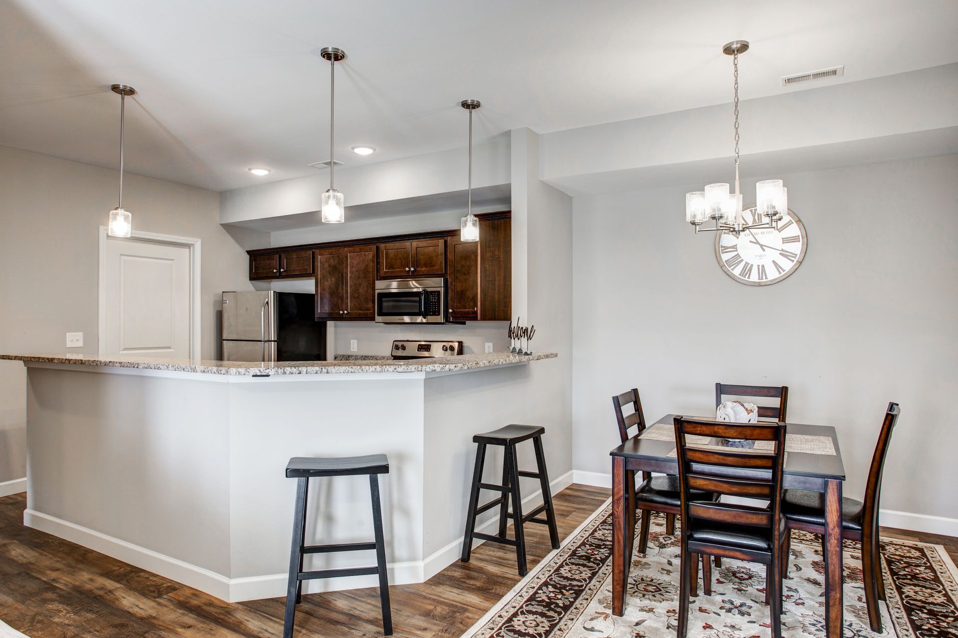 A kitchen with a table and chairs and a clock on the wall.