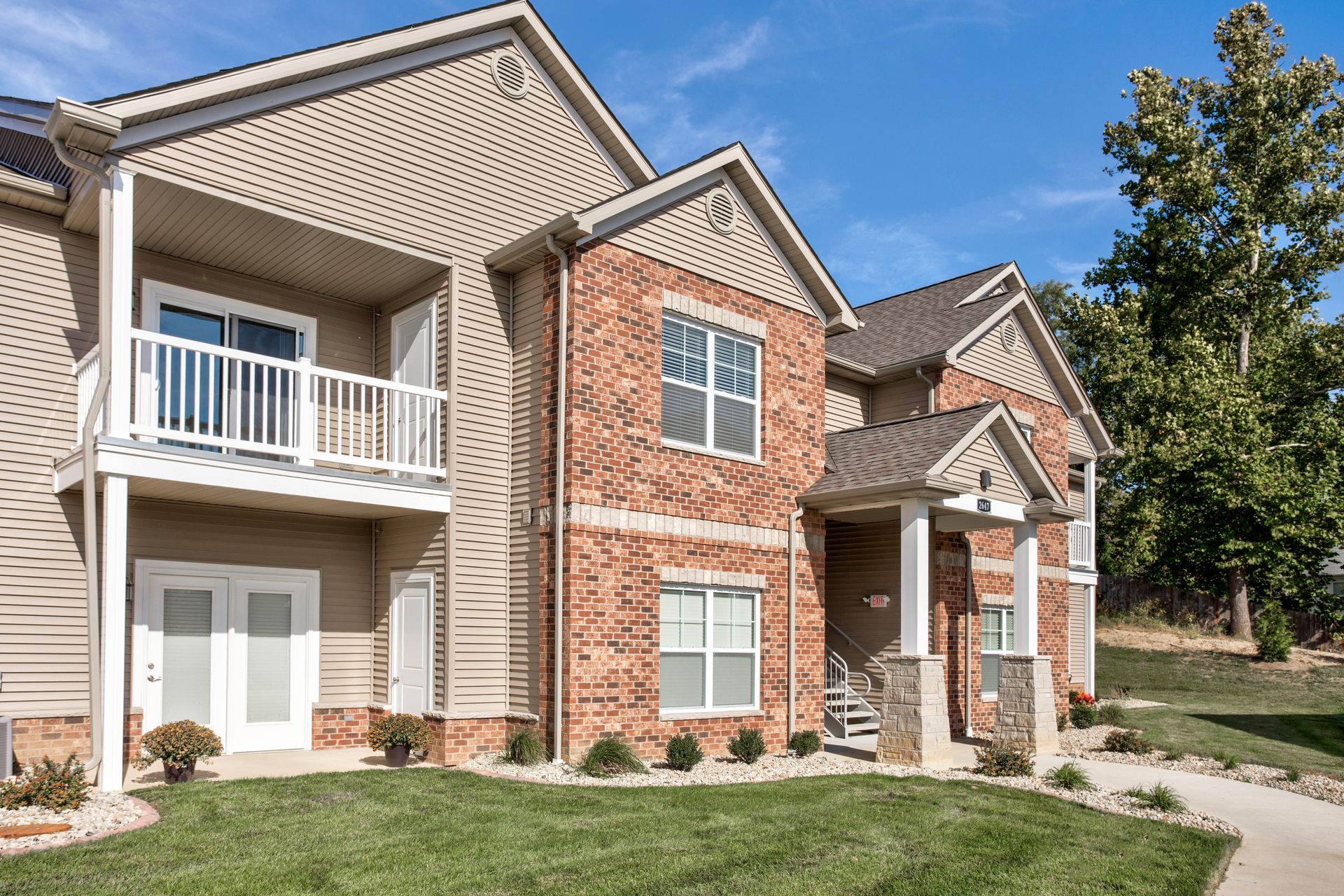 A large brick apartment building with a lush green lawn in front of it.