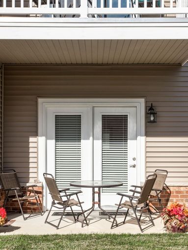 A patio with a table and chairs in front of a house