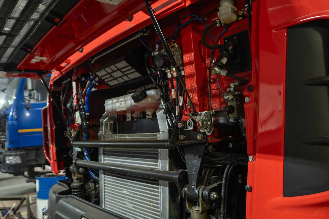 Close-up of a modern truck radiator and cooling system assembly under a red cabin.