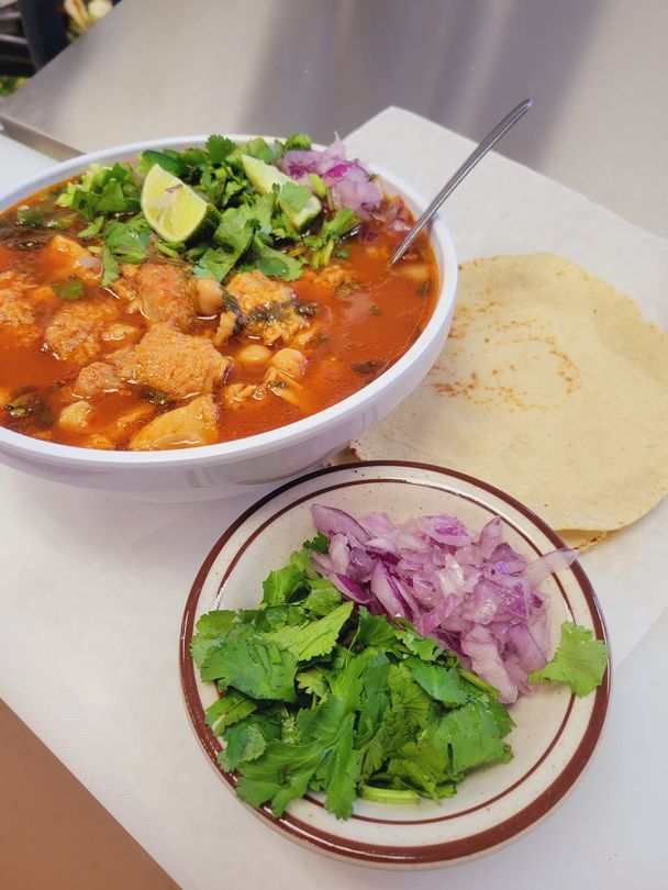 A bowl of soup and a plate of vegetables on a table.