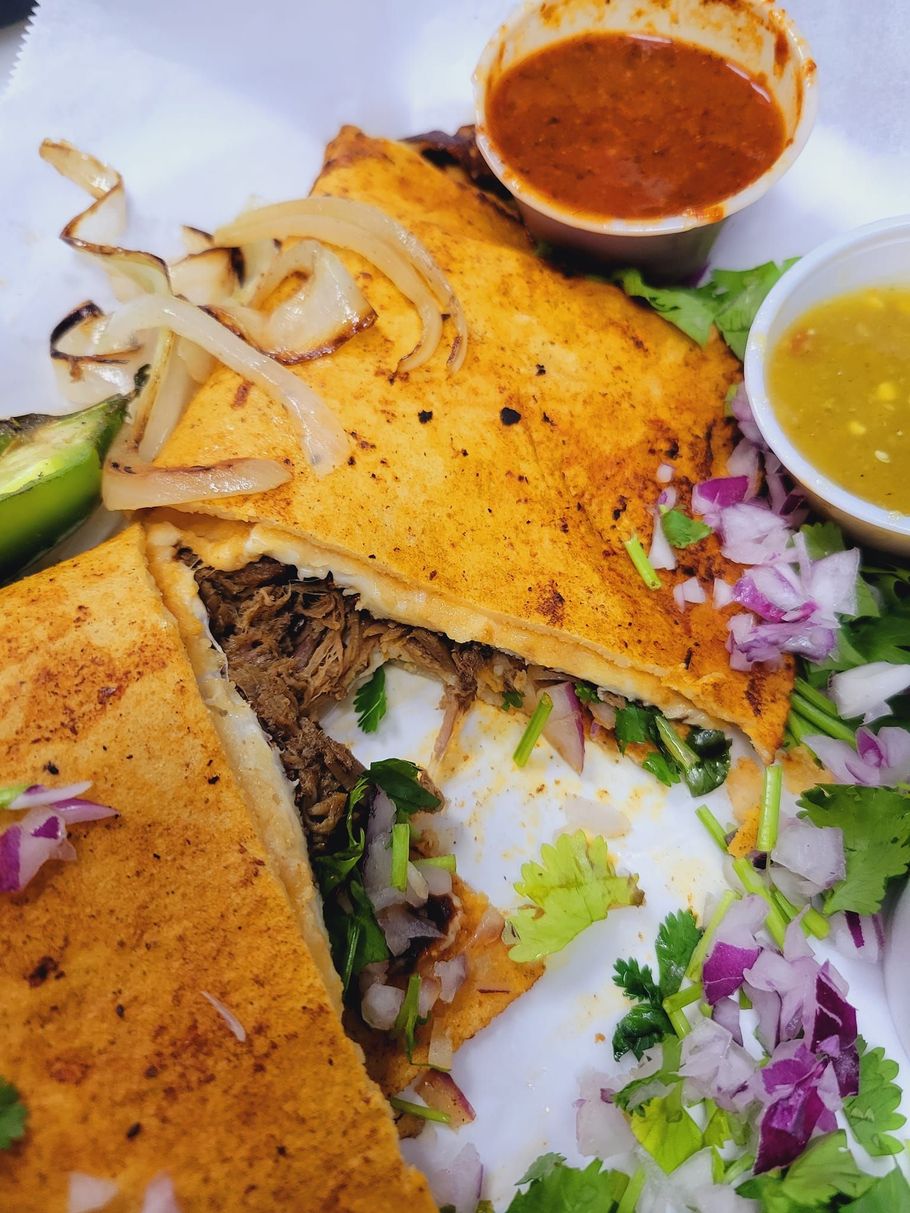 A close up of a sandwich with meat and vegetables on a plate.