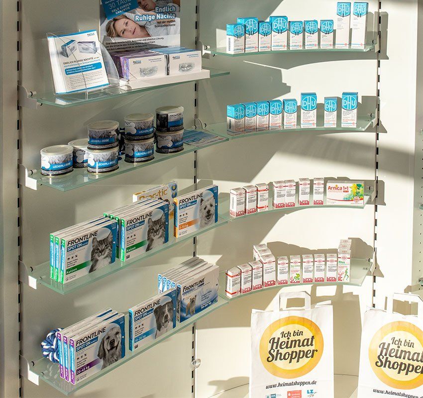 In einem Einzelhandelsgeschäft werden in den Regalen verschiedene Tierpflegeprodukte und Medikamente ausgestellt, darunter befinden sich Einkaufstaschen der Marke „Heimat Shopper“.