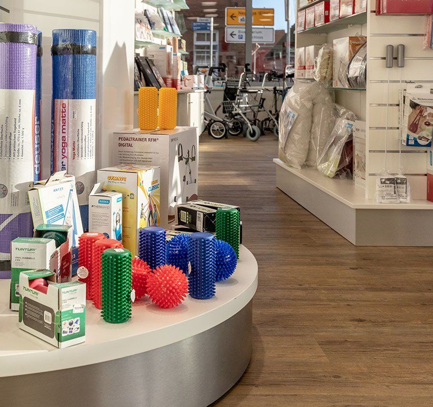 Auf einem runden Tisch ist ein Verkaufsdisplay mit Yogamatten, verpackten Gesundheitsprodukten und verschiedenen farbenfrohen Massagebällen mit unterschiedlichen Texturen zu sehen.