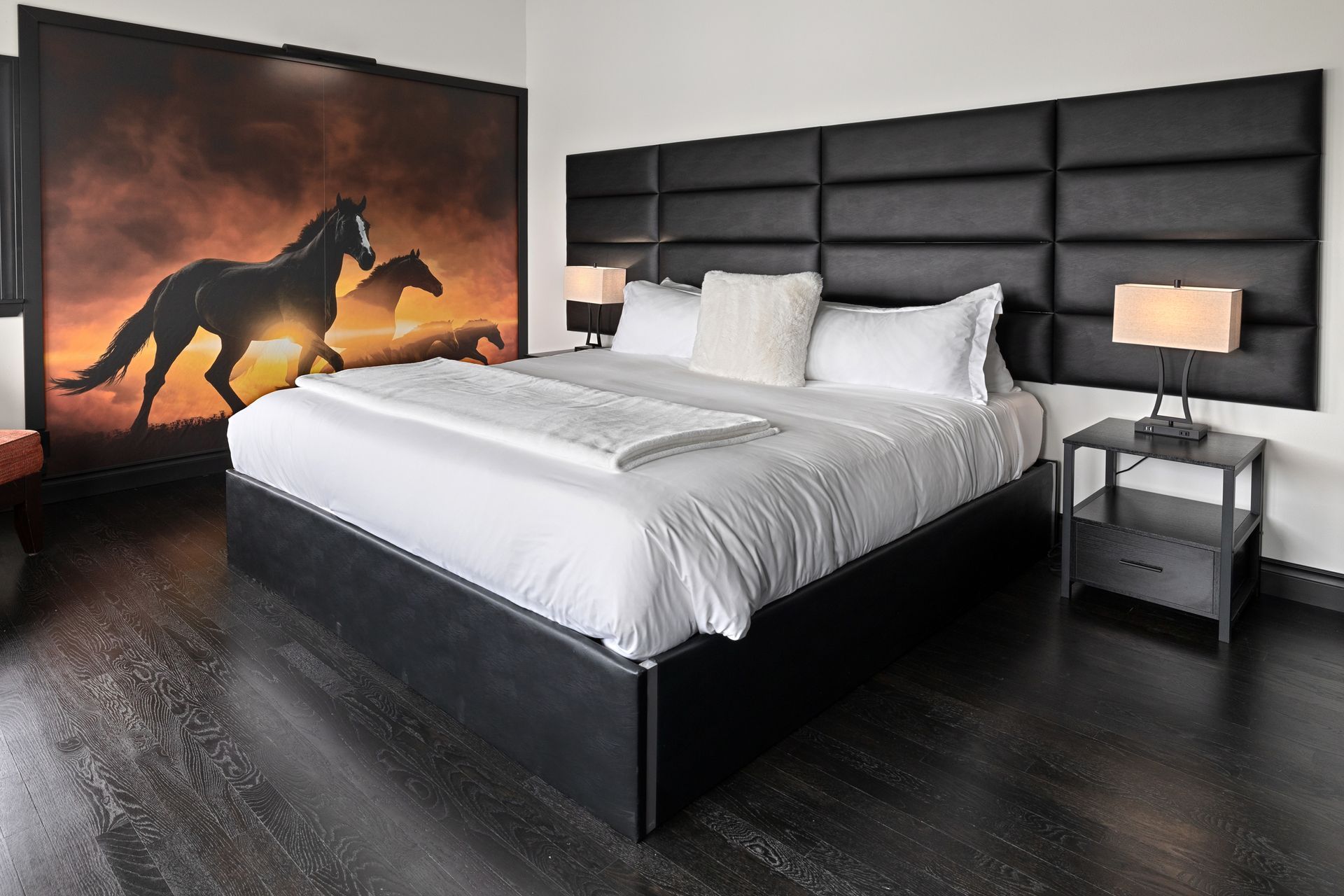 Bedroom with a black bed, headboard, and dark wood floor. A horse mural is on the wall. Best lodging in central WA