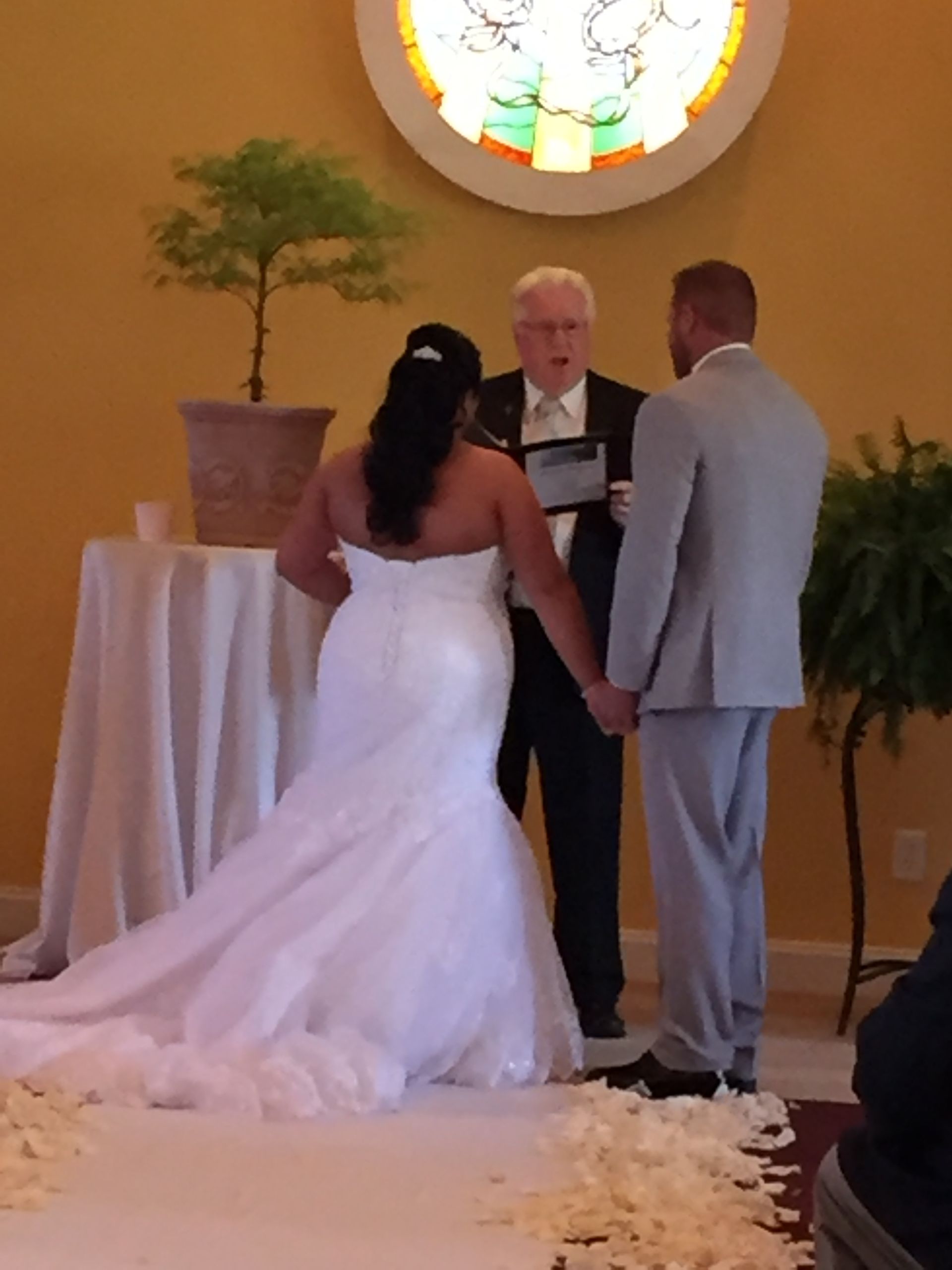 A bride and groom hold hands during their wedding ceremony