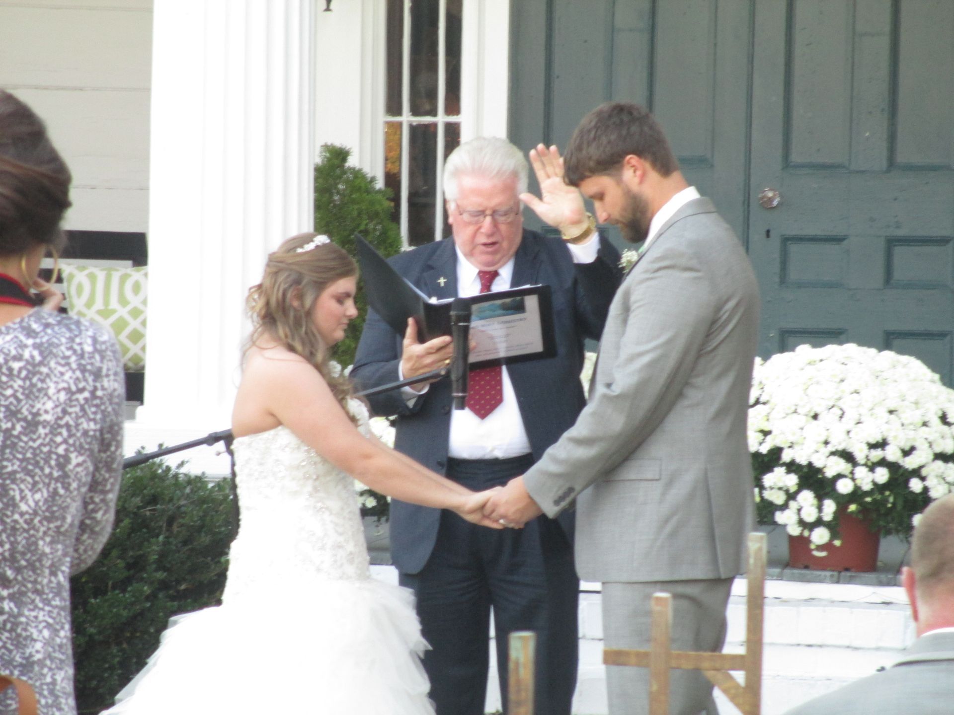 A bride and groom are holding hands during their wedding ceremony