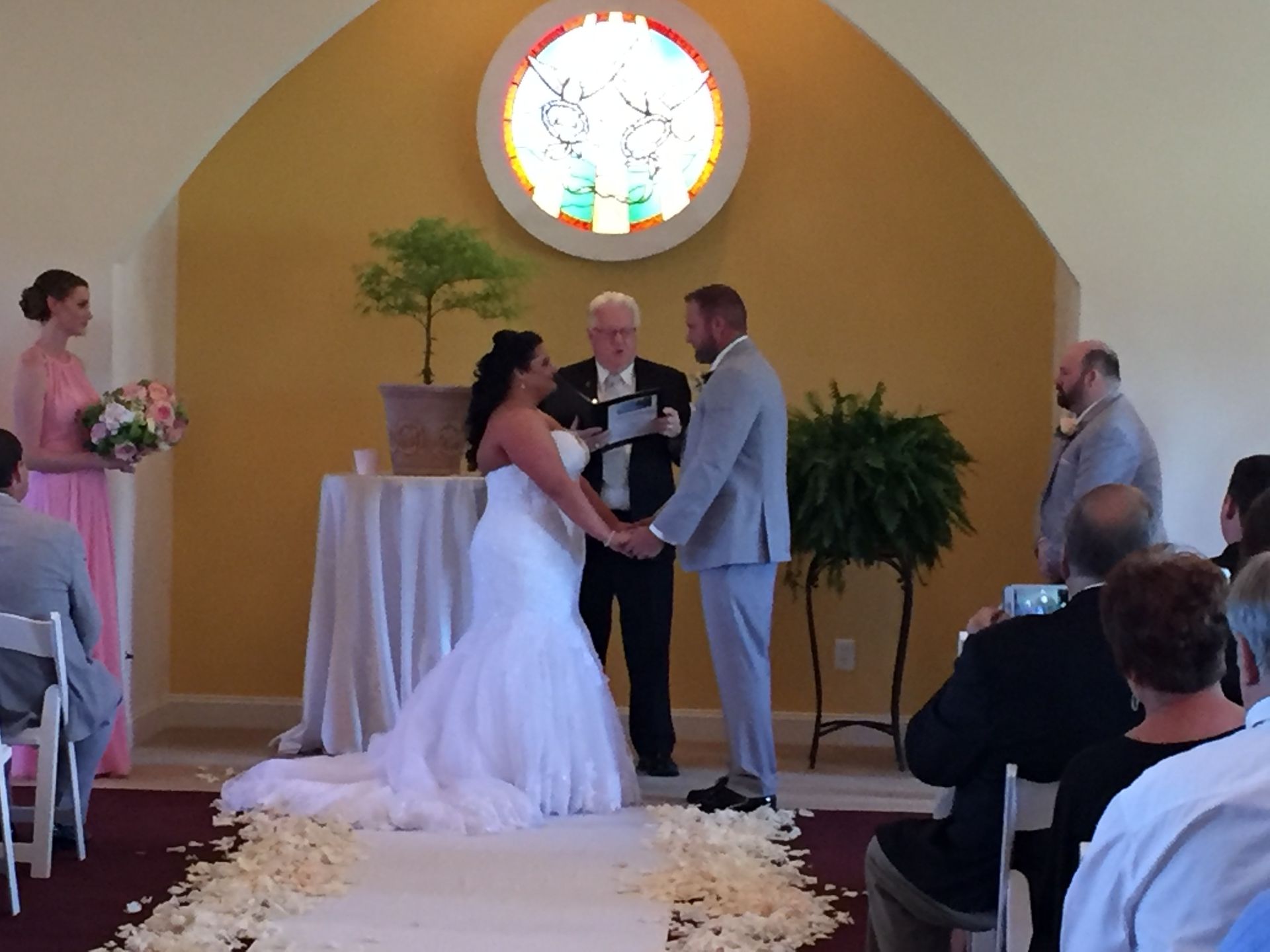 A bride and groom are holding hands during their wedding ceremony