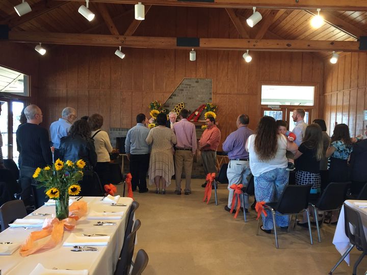A group of people are standing in a room with tables and chairs.