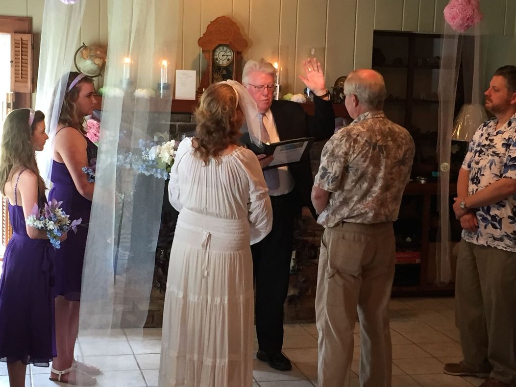 A bride and groom are getting married in front of a group of people