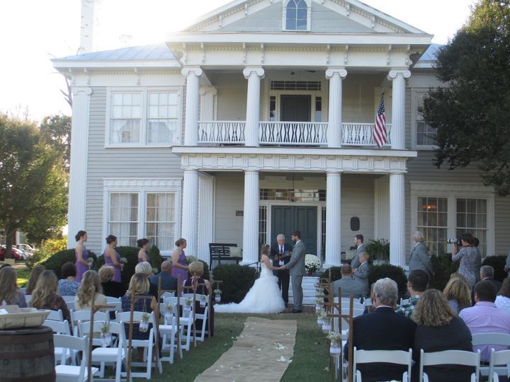 A bride and groom are getting married in front of a large house