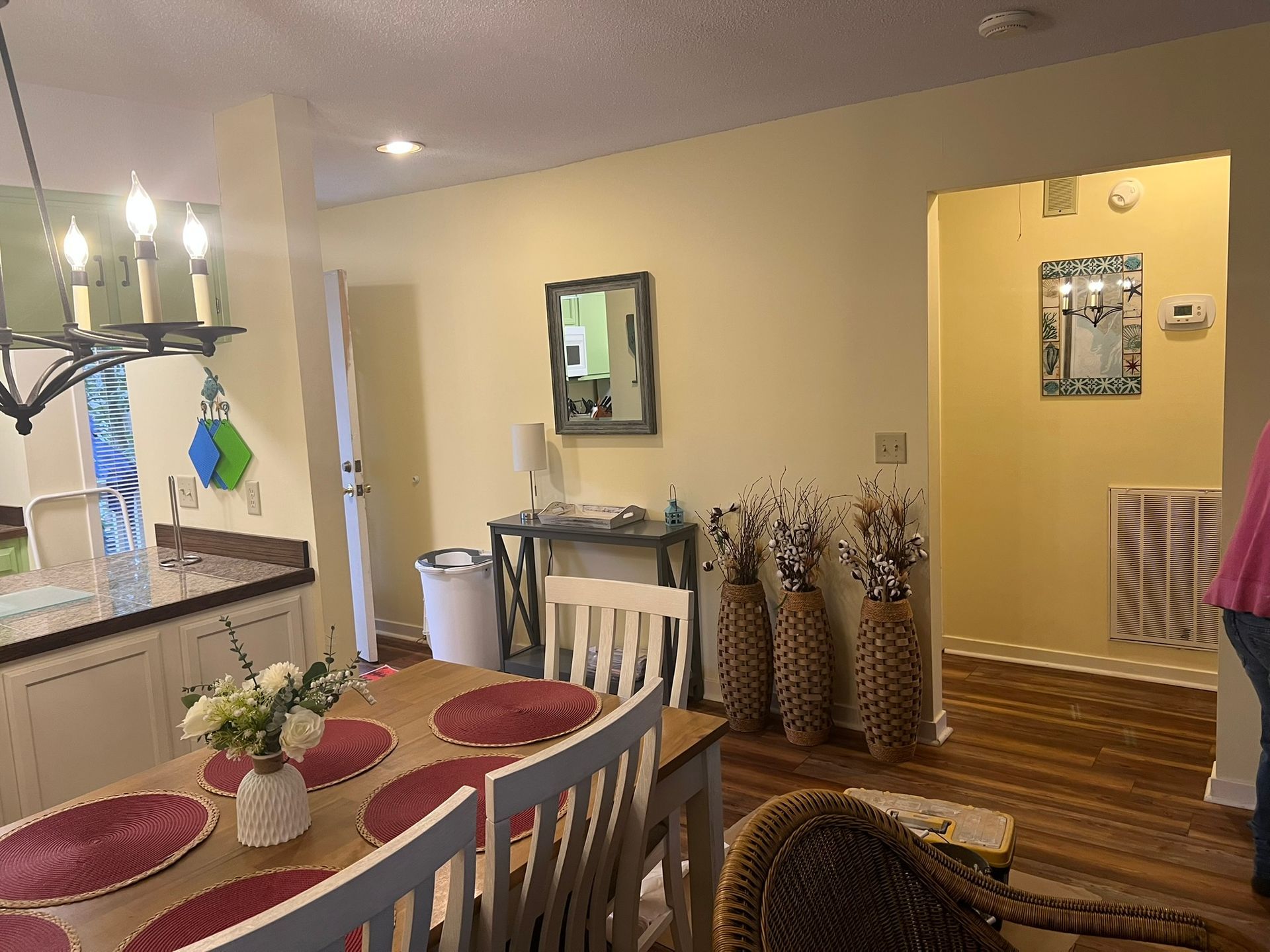 A dining room with a table and chairs and a mirror on the wall.