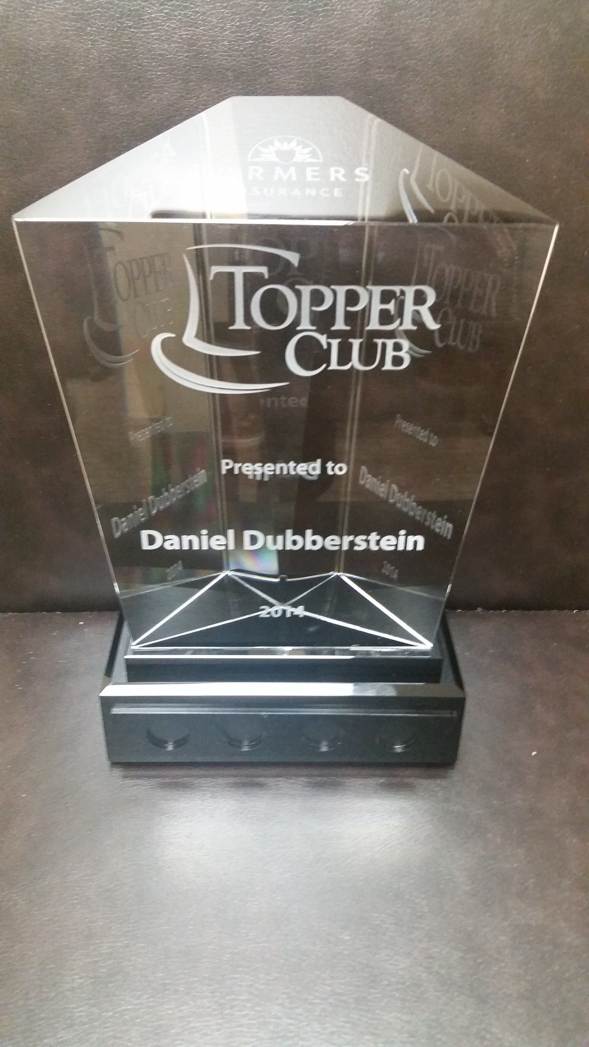 Clear award plaque reading “Topper Club” and “Presented to Daniel Dubberstein” on a dark base