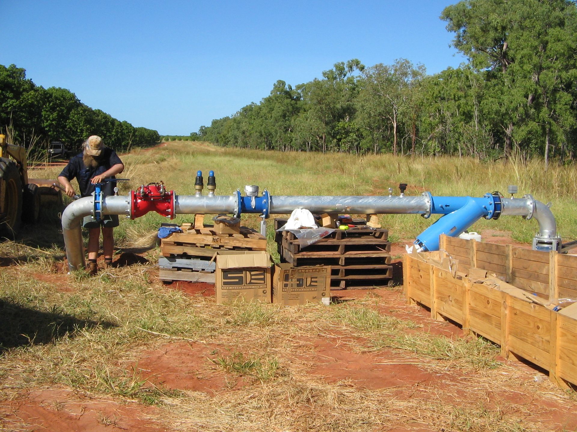 A man is working on a large pipe in a field