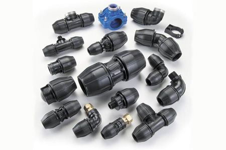 A variety of plastic pipe fittings are sitting on top of each other on a white surface.