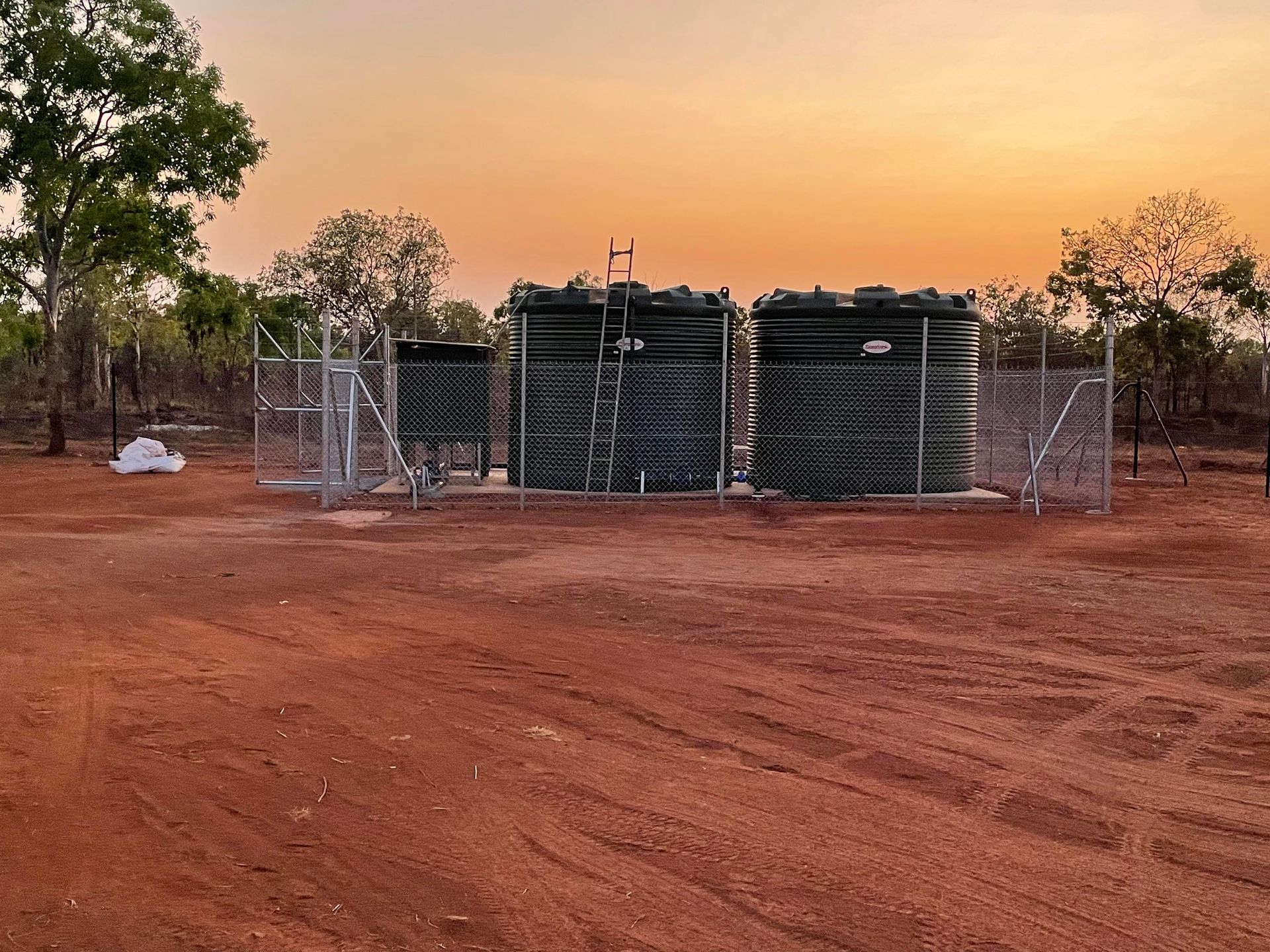 A fenced in area with a sunset in the background