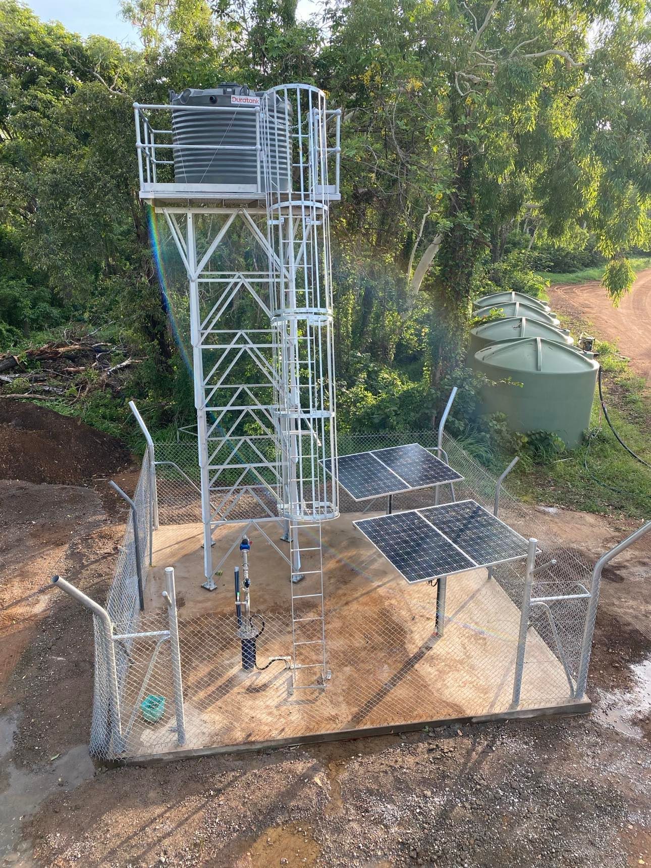 A fenced in area with a water tower and solar panels.