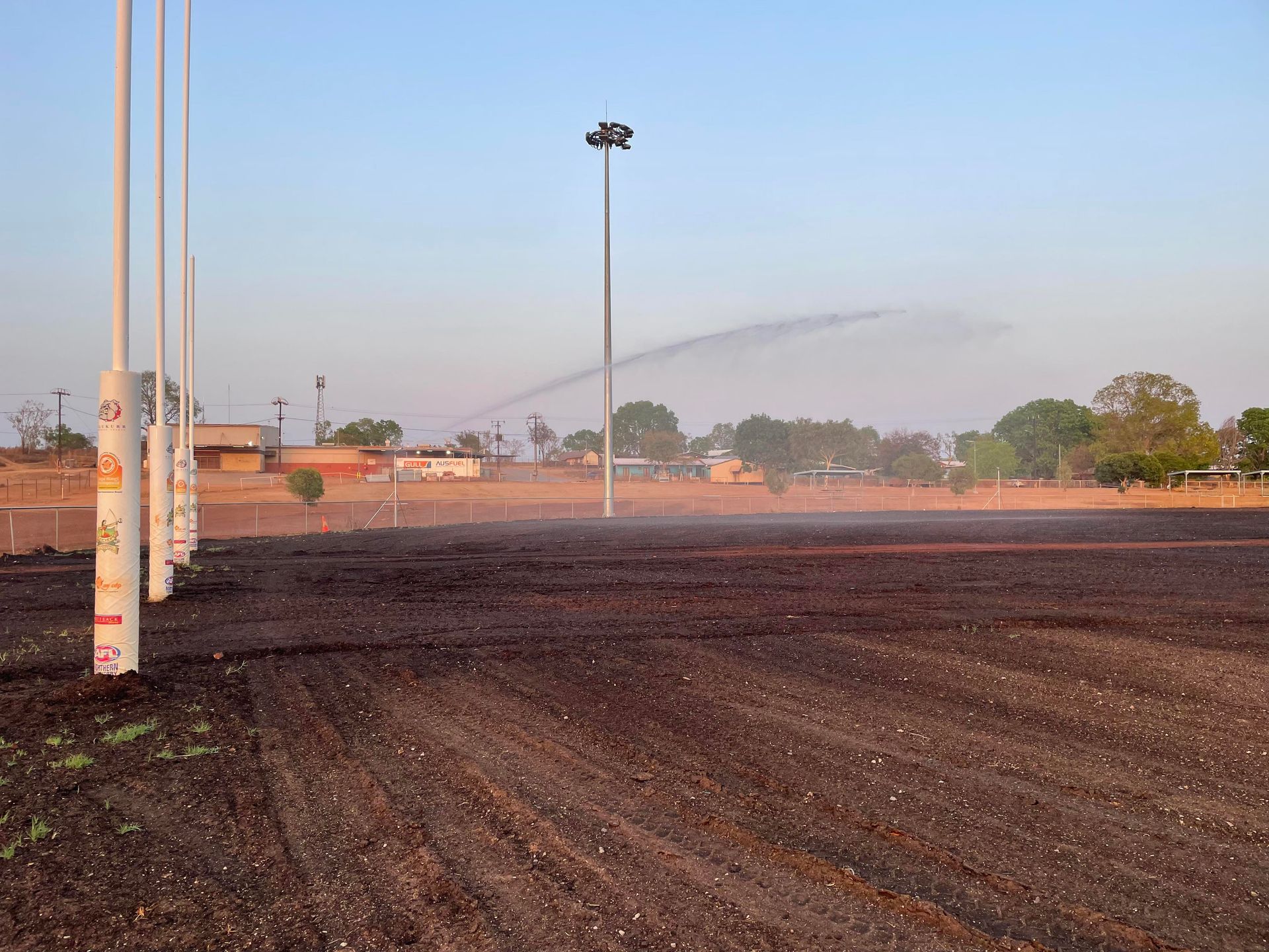 A sprinkler is spraying water on a dirt field