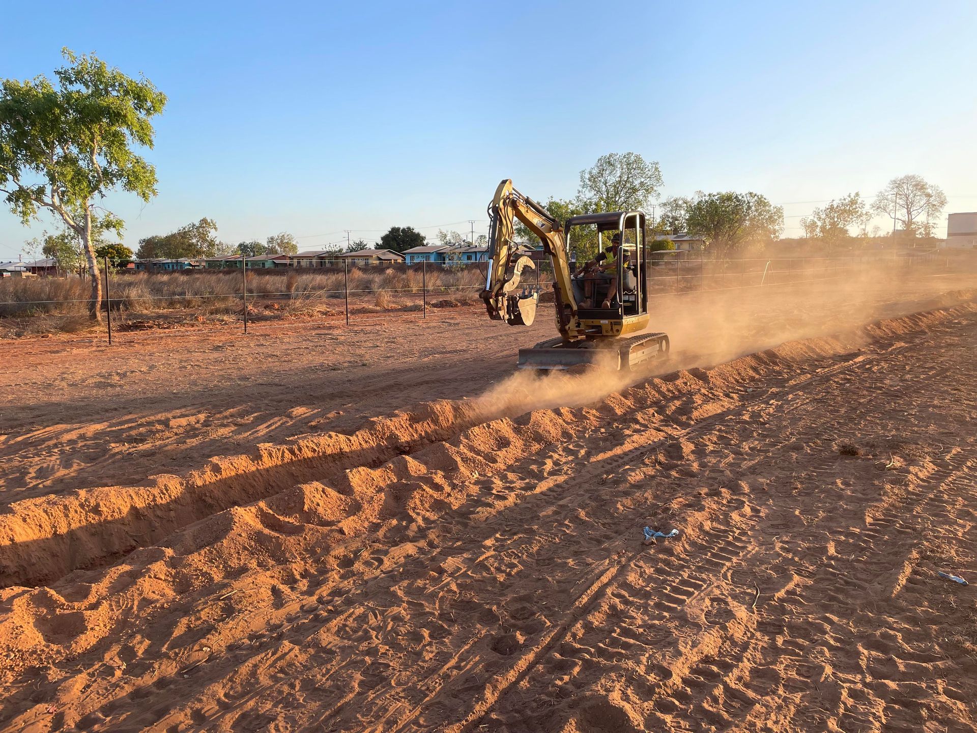 A small excavator is moving dirt in a field.
