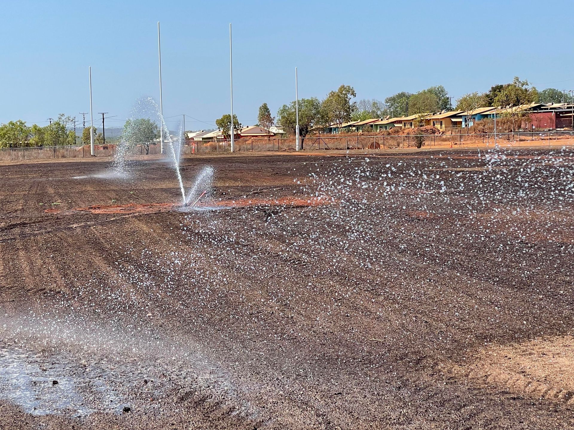 A sprinkler spraying water on a dirt field