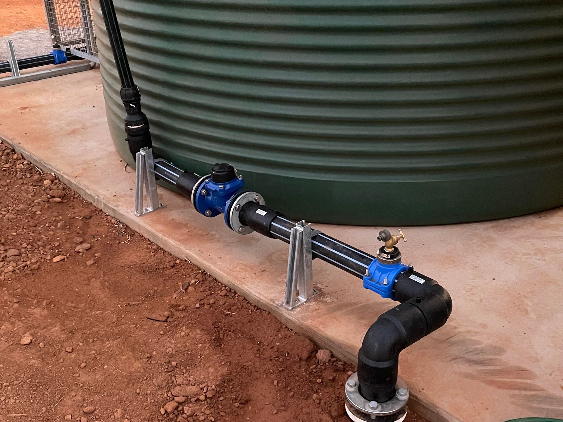 A green water tank with blue pipes attached to it.