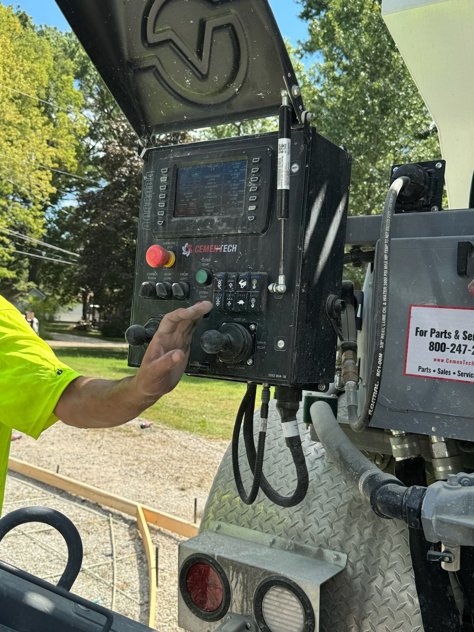 Worker using a control panel on a street maintenance truck with the hatch open