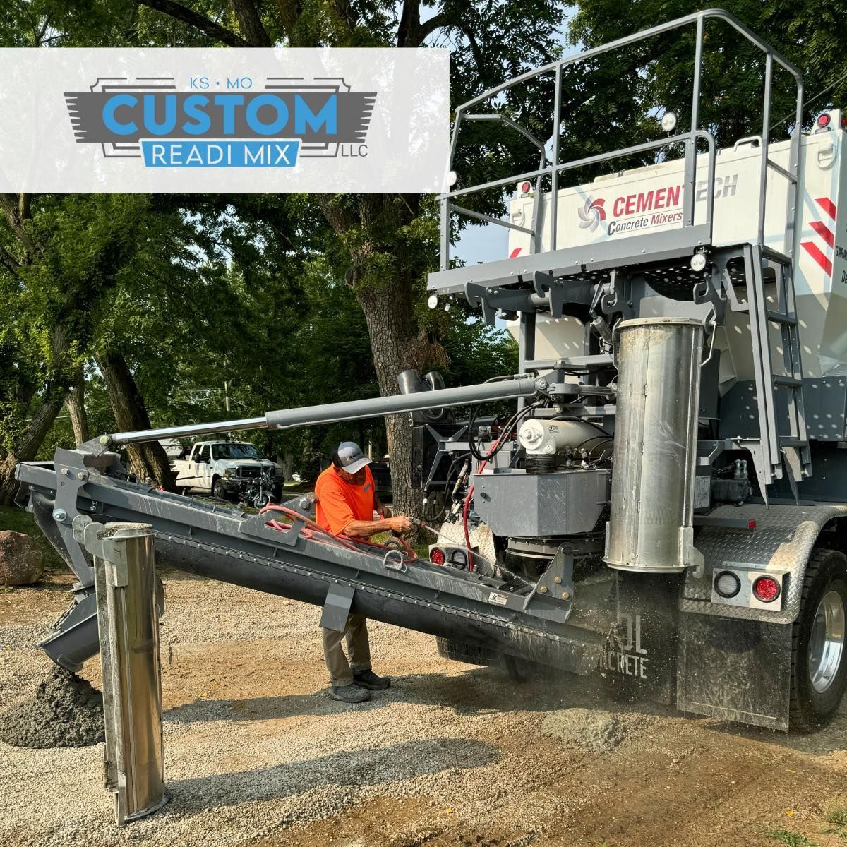 Worker beside concrete mixer truck and conveyor chute at a gravel site