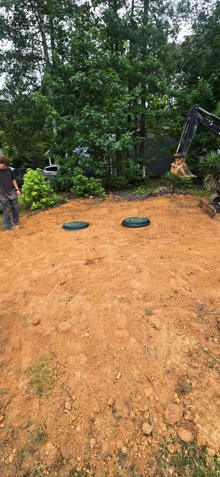 Two green bags on a reddish dirt slope with trees in the background
