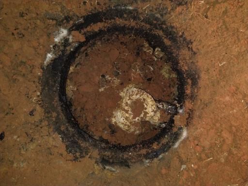 A weathered black ring painted on a brown, dirt-covered surface