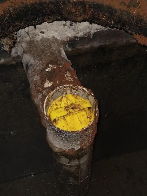 Rusty metal pipe with a yellow capped end against a dark background