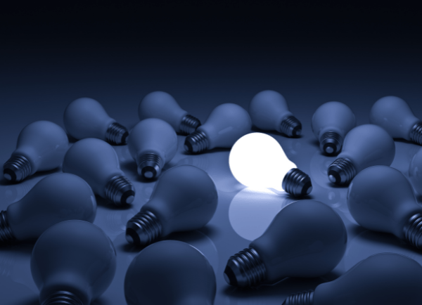 one lightbulb lit on a table with others burnt out