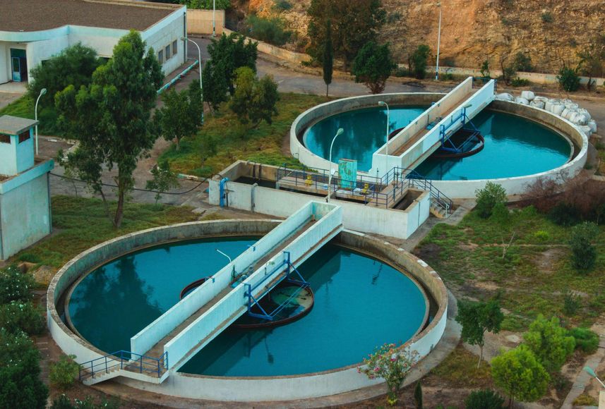 Aerial view of a wastewater treatment plant with two circular sedimentation tanks and water.