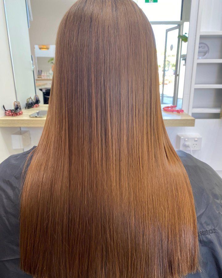 A Woman With Long Brown Hair Is Sitting In A Chair In Front Of A Mirror — The Hair Boutique Co In Varsity Lakes, QLD