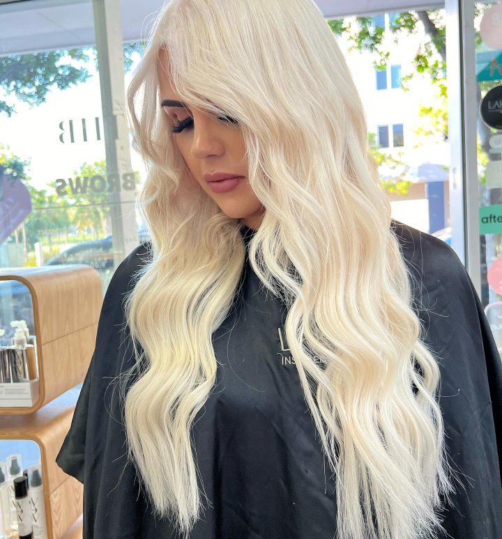 A Woman With Long Blonde Hair Is Wearing A Black Cape — The Hair Boutique Co In Varsity Lakes, QLD