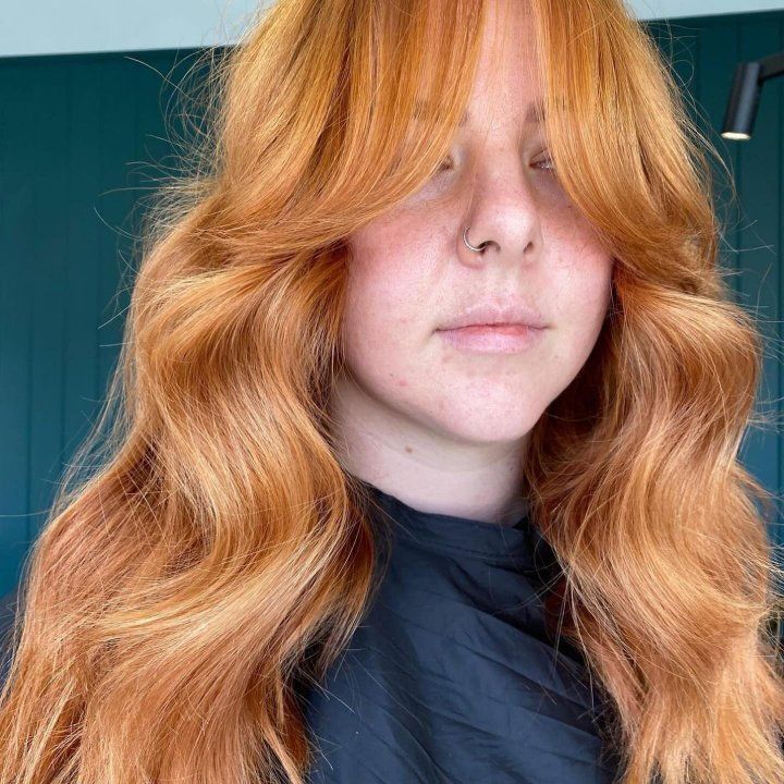 A Woman With Long Red Hair And Bangs Is Wearing A Black Shirt — The Hair Boutique Co In Varsity Lakes, QLD
