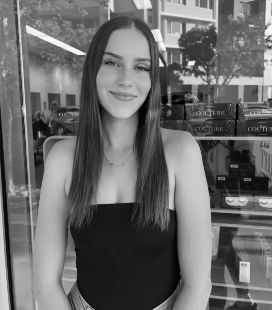 A black and white photo of a woman standing in front of a window.