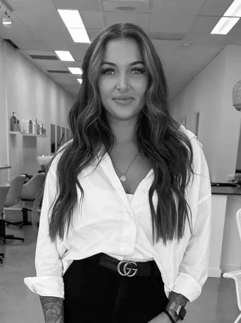 A woman in a white shirt and black pants is standing in a room in a black and white photo.