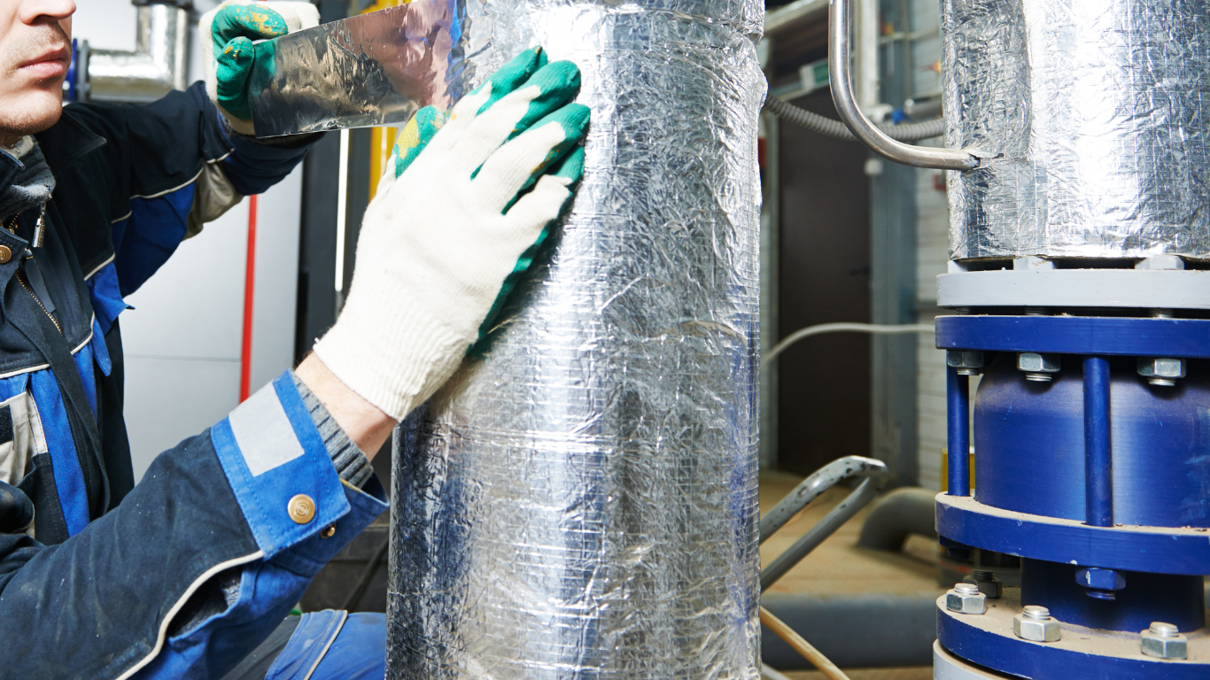 Worker in hard hat tightening a pipe valve at an industrial refinery